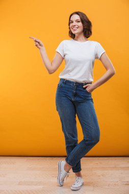 Görüntü izole kamera seyir boşaltmak gösterilen sarı arka plan üzerinde duran heyecanlı genç kadın.