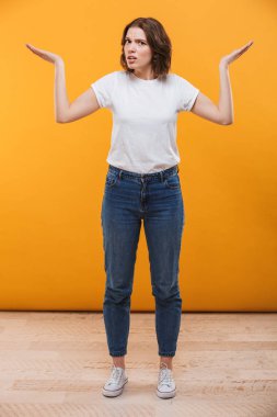 Karışık genç bayan kamera seyir sarı arka plan üzerinde izole ayakta görüntüsünü.