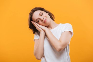 Sarı arka plan üzerinde izole ayakta uyuyan sevimli genç bayan görüntüsünü.