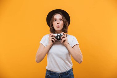Görüntü izole kamera tutarak sarı arka plan üzerinde duran heyecanlı duygusal genç kadın fotoğrafçı turist.