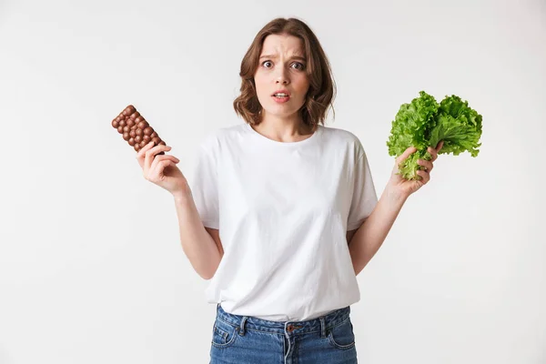 Porträt Einer Verwirrten Jungen Frau Mit Schokoriegel Und Salat Auf — Stockfoto