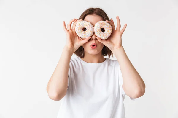 一个微笑的年轻女子的肖像持有两个甜甜圈在她的脸上孤立的白色背景 — 图库照片
