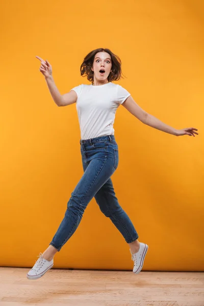 Photo Emotional Young Woman Jumping Isolated Yellow Background Looking Camera — Stock Photo, Image