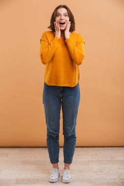 Kazaklı ağız ile heyecanlı bir genç kadın portresi tam uzunlukta sarı arka plan üzerinde açın