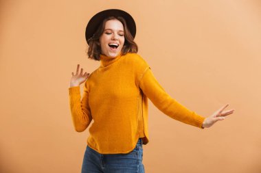 Görüntü şaşırtıcı genç kadın dans görünümlü kamera şapka izole.