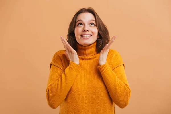 一个兴奋的年轻女子在毛衣的肖像庆祝成功和查找米色背景 — 图库照片