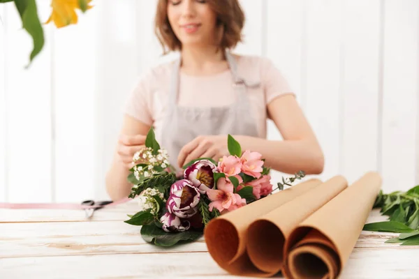 ワーク ショップのテーブルにさまざまな花の花束を集める若い花屋女性のぼやけた写真 — ストック写真