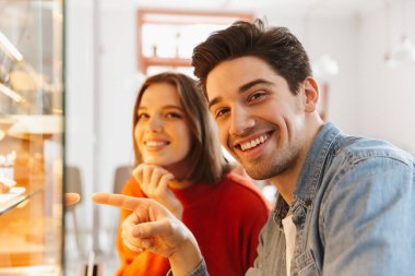 Kadın güzel çift ve casual adam gülümseyerek ve rahat ekmek lezzetli pastalar parmak işaret giymek