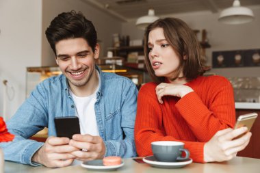 Mutlu adam Cafe meraklı kadın onun smartphone içinde gözatma sırasında cep telefonuyla görüntü