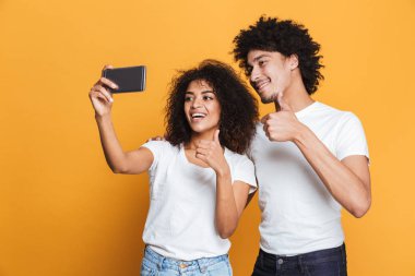Sarı arka plan üzerinde izole bir selfie alarak bir neşeli genç afro Amerikan çift portresi