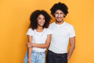 Sarılma bir gülümseyen genç afro Amerikan Çift sarı arka plan üzerinde izole portresi
