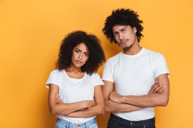 Silah ile bir üzgün genç afro Amerikan çift ayakta portresi izole sarı arka plan üzerinde katlanmış