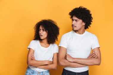 Silah ile ayakta bir üzgün genç afro Amerikan çift portresi katlanmış ve seyir uzağa izole sarı arka plan üzerinde