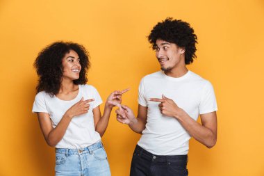 Birbirimize izole sarı arka plan üzerinde parmakları işaret hoş bir genç afro Amerikan çift portresi