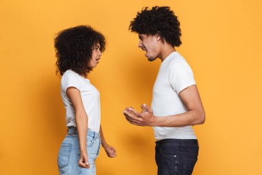 Kızgın bir afro Amerikan Çift sarı arka plan üzerinde izole bir tartışmayı portresi