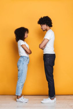 Üzgün bir afro Amerikan Çift sarı arka plan üzerinde izole bir tartışmayı tam uzunlukta portresi