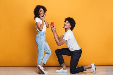 Sarı arka plan üzerinde izole kız arkadaşı için teklif neşeli bir Afrika adam portresi