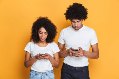 Genç afro Amerikan çift cep telefonları üzerinde sarı arka plan izole kullanarak portresi