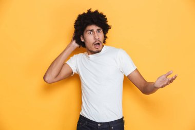 Karışık bir genç Afrika adam açık ağızlı sarı arka plan üzerinde izole kameraya bakarak portresi
