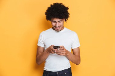 İstimal hareket eden telefon bir izole sarı arka plan üzerinde mutlu bir genç Afrika erkek portresi