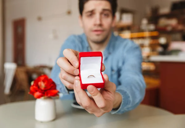 カフェのテーブルに座って カメラでの婚約指輪のボックスを発揮しながら彼のガール フレンドに提案している興奮している男のぼやけた写真 — ストック写真