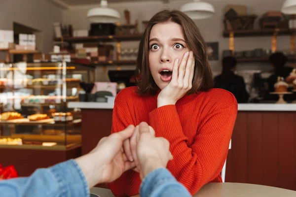 Photo of excited woman expressing surprise with open mouth while man holding her hand with proposal