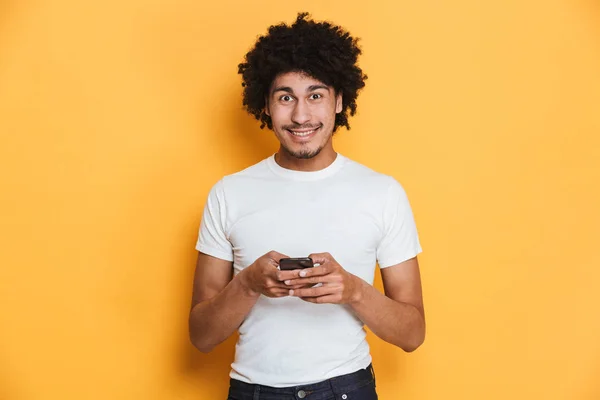 一个快乐的年轻非洲家伙的肖像手持手机一个孤立的黄色背景 — 图库照片