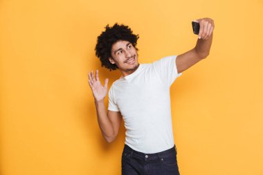 Neşeli bir genç Afrika adam sarı arka plan üzerinde izole bir selfie alarak portresi
