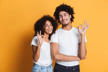 Mutlu bir afro Amerikan çift ok hareket izole sarı arka plan üzerinde gösterilen portresi