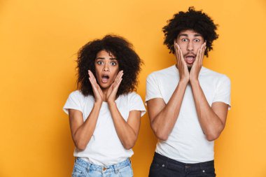 Çığlık bir sürpriz genç afro Amerikan çift sarı arka plan üzerinde izole portresi