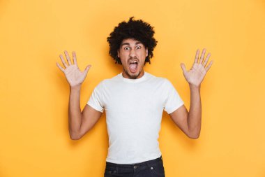 Korkmuş genç Afrika adam kaldırdı elleriyle çığlık sarı arka plan üzerinde izole bir portresi