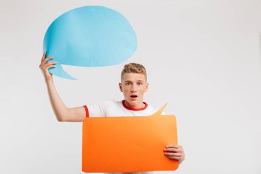 Görüntü iki ticari afişlerin boşaltmak izole beyaz arka plan üzerinde metniniz için tutan temel t-shirt giyen şok erkek öğrenci