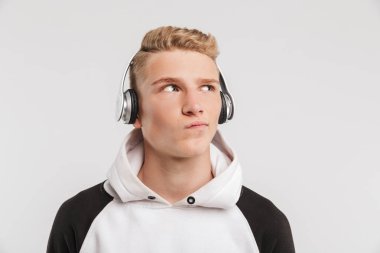 Şık gencin düşünme ve bir kenara bükülmüş ağzıyla beyaz arka plan üzerinde izole kablosuz kulaklık ile müzik dinlerken arıyorum eski portre portre