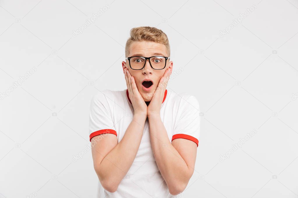 Photo of surprised guy in eyeglasses screaming and grabbing face in fear or shock isolated over white background
