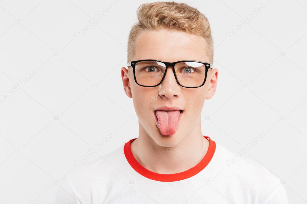 Image closeup of blond funny boy having clean healthy skin wearing eyeglasses playing around and showing tongue at camera isolated over white background