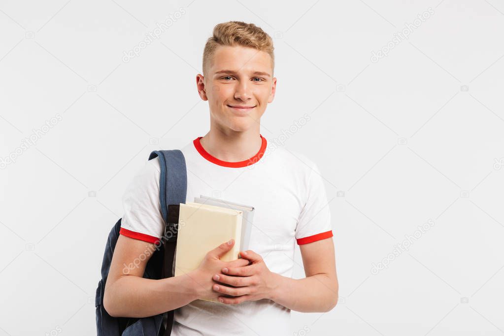 Image of smart content student guy wearing backpack smiling and looking at you with books in hands isolated over white background