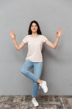 Görüntü güzel genç bayan gri arka plan duvardan izole meditasyon.