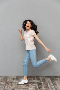 Görüntü izole kamera seyir gri arka plan duvardan atlama güzel genç kız.
