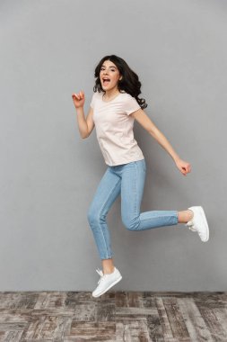Görüntü izole kamera seyir gri arka plan duvardan atlama güzel genç kız.