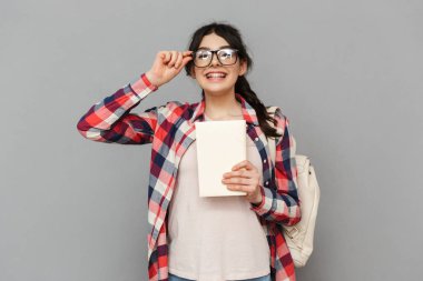 Görüntü çok hoş genç bayan öğrenci kitap gri arka plan duvardan izole ayakta.