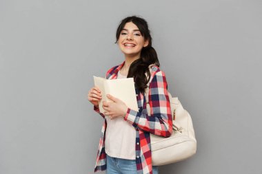 Görüntü çok hoş genç bayan öğrenci kitap gri arka plan duvardan izole ayakta.