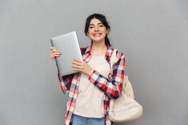 Görüntü gri arka plan duvar gösteren dizüstü bilgisayar üzerinde izole ayakta inanılmaz duygusal genç bayan öğrenci.