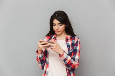 Görüntü gri arka plan duvar izole sevimli genç bayan oyun oyunlar cep telefonu tarafından.