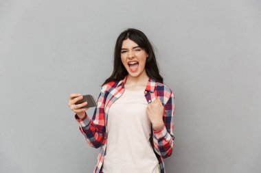 Kazanan jest yapmak imge-in duygusal genç bayan gri arka plan duvar oyun oyunlar üzerinden cep telefonuyla izole.