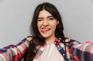 Selfie kamera gösteren dil seyir yapmak imge-in sevimli güzel genç bayan gri arka plan duvardan izole.