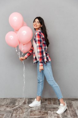 Sevimli güzel genç bayan balon tutan gri arka plan duvardan izole görüntüsünü.
