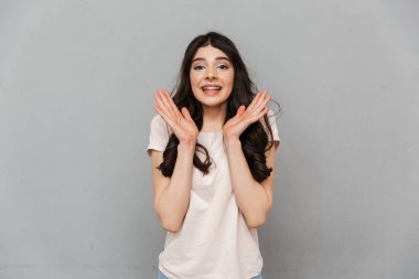 Heyecanlı güzel genç bayan gri arka plan duvardan izole ayakta görüntüsünü.