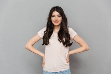 Sevimli güzel genç bayan gri arka plan duvardan izole ayakta görüntüsünü.