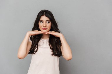 Sevimli güzel genç bayan gri arka plan duvardan izole ayakta görüntüsü. Bir kenara arıyorsunuz.