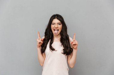 Duygusal güzel genç bayan gri arka plan duvar işaret içinde izole ayakta görüntüsünü.